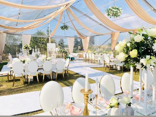 a wedding marquee with white tables and chairs and flowers at Ekupholeni Garden Villas in Manzini