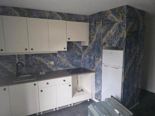 a kitchen with white cabinets and a marble wall at Erholung am Vierwaldstättersee, komfortables 3-Bett-Zimmer in Brunnen in Brunnen