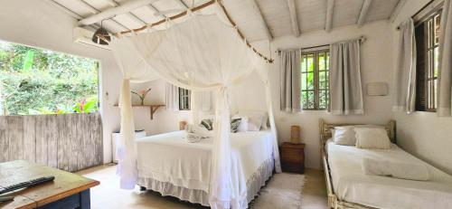 a bedroom with a white bed with a canopy at Vila Pitanga Trancoso in Trancoso