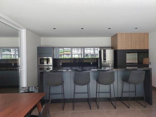 a kitchen with a bar with stools in it at Loft av central in Xangri-lá