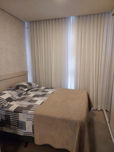 a bedroom with a bed and a window with curtains at Loft av central in Xangri-lá