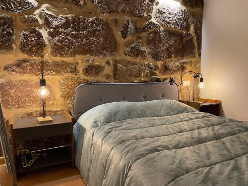a bedroom with a bed and a stone wall at Casa do Terrado in Tourém