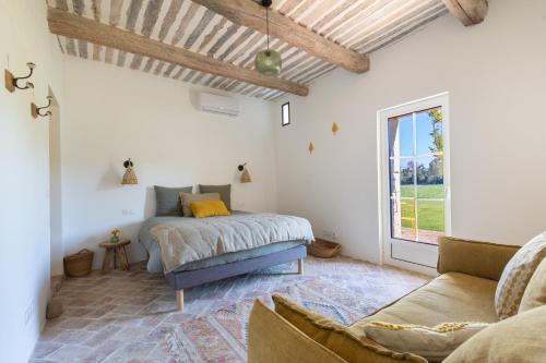 a bedroom with a bed and a couch and a window at Terres Élaïs in Robion en Luberon