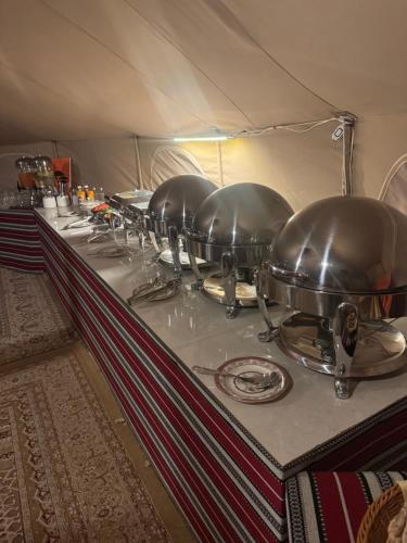 BadīyahにあるDesert Stars Campのテント内のテーブルの上に並べられた鍋やフライパン