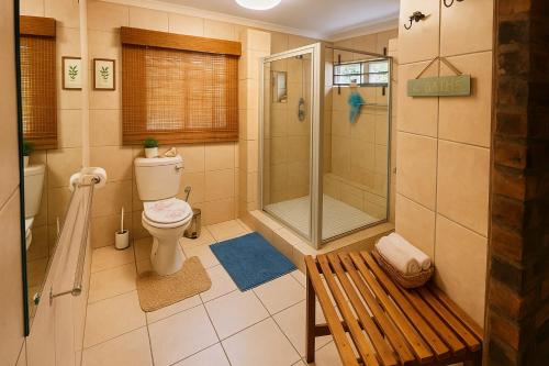 a bathroom with a shower and a toilet and a bench at Tree Lodge by My Adventure House in Marloth Park