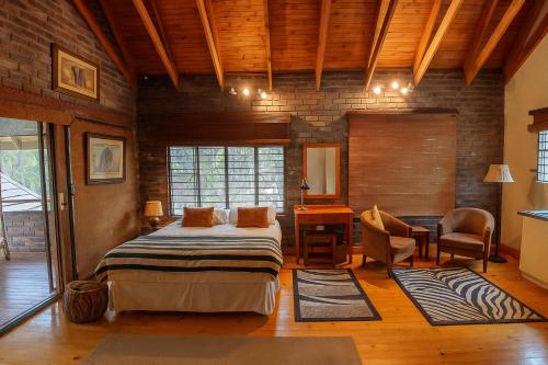 a bedroom with a bed and a desk and chairs at Tree Lodge by My Adventure House in Marloth Park