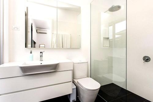 Un baño blanco con lavabo y ducha. en Stonecutters 2, en Byron Bay