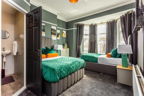 two beds in a room with green walls at Sandhaven House in South Shields