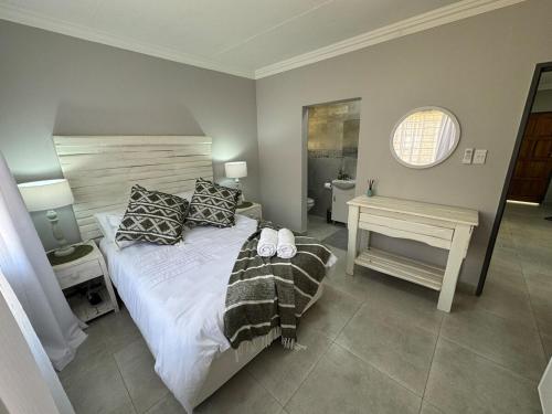 a bedroom with a bed and a table and a window at Urban Bliss Villa in Klerksdorp