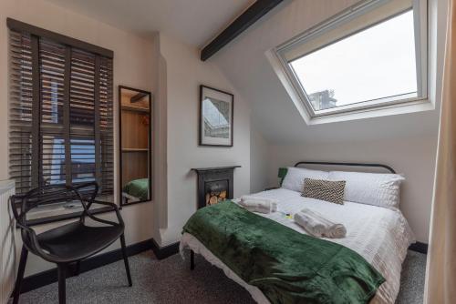 a bedroom with a bed and a chair and a window at 4 bedroom 2 bath beautiful Victorian house in Nottingham