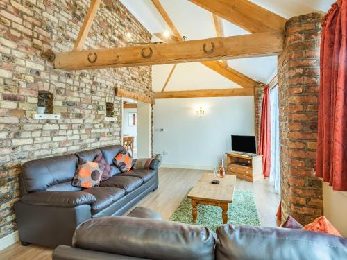 ein Wohnzimmer mit einer Couch und einer Ziegelwand in der Unterkunft The Forge - Uk37519 in Routh