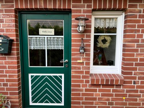 Una puerta verde en una casa de ladrillo con una ventana. en Hümmling HA16, en Sögel