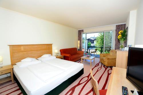 a bedroom with a bed and a living room at Das Hotel Eden - Das Aktiv- & Wohlfühlhotel in Tirol auf 1200m Höhe in Seefeld in Tirol