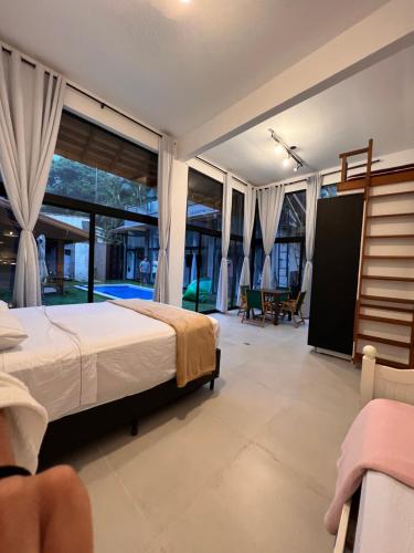 ein Schlafzimmer mit Bett und großen Fenstern in der Unterkunft CasadevidroTTP Pé na areia in São Sebastião