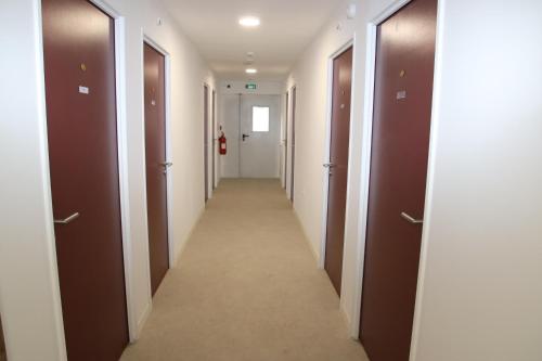 Un pasillo de un pasillo con puertas marrones. en Arkenciel, en Mudaison