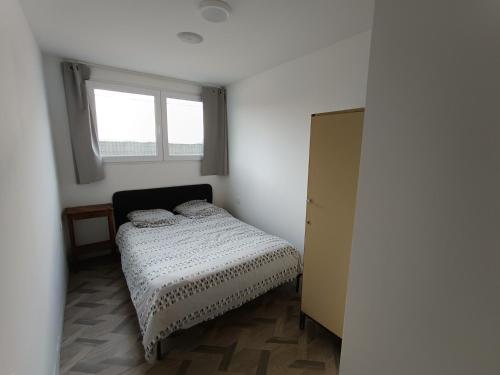 una piccola camera da letto con un letto e una finestra di Arkenciel a Mudaison