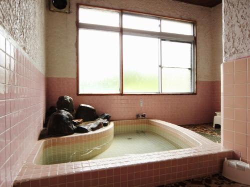 飯山市的住宿－童話屋斑尾賓館，一个带窗户的客房内的按摩浴缸