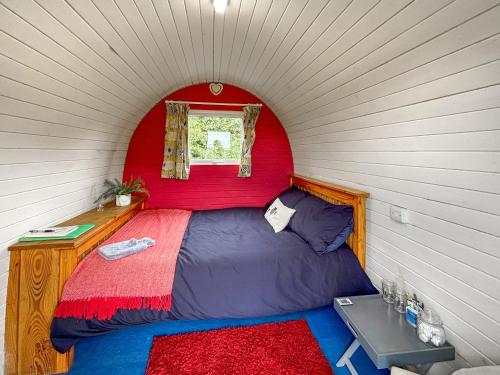 a bed in a red room with a window at The Sheep Pod - Uk50074 in Welshpool