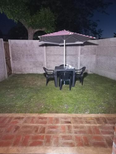 a table and two chairs under an umbrella at Hospedaje la querencia in San Antonio de Areco