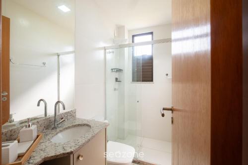 Un baño con ducha de cristal y lavabo. en Condominio con Piscina a 450m de la Playa en Itacimirim - VBRs, en Pojuquinhos