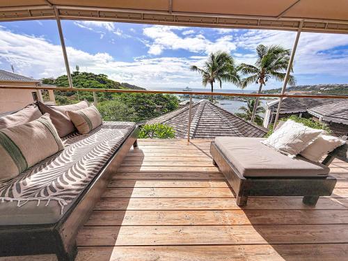 a balcony with a couch on a wooden deck at Villa Olive Sea View Cocoon in Oyster Pond in Oyster Pond