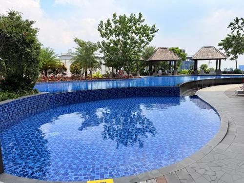 a large blue swimming pool with a bridge in a resort at Apartment Podomoro Lincoln Delipark in Medan