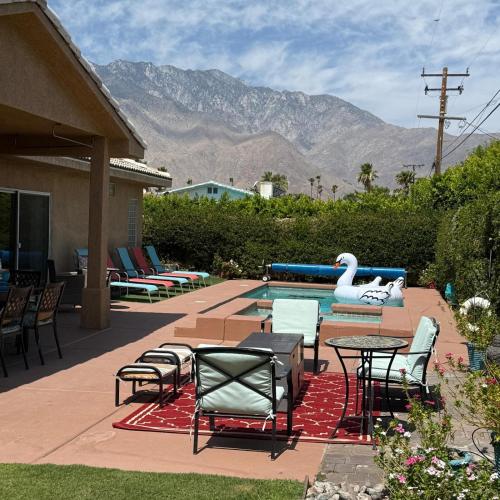 a patio with chairs and tables and a swimming pool at Swan House in Palm Springs