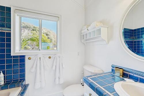 een blauwe en witte badkamer met een wastafel en een raam bij Perched on the Bluff - Casita in Mendocino
