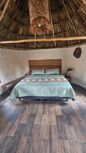 a bedroom with a bed with a straw roof at Cabañas Los Gallitos Ecolodge 3 in Sacalum