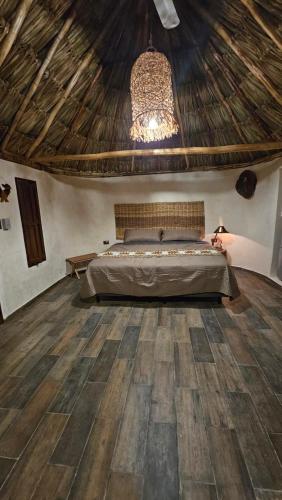 a bedroom with a bed and a wooden floor at Cabañas Los Gallitos Ecolodge 3 in Sacalum