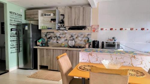 a kitchen with a table and a refrigerator at Casa Completa & Confortável há 25min de Corinthians Itaquera in Sao Paulo