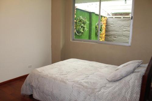 a bedroom with a white bed and a window at Departamento La República in Cuenca