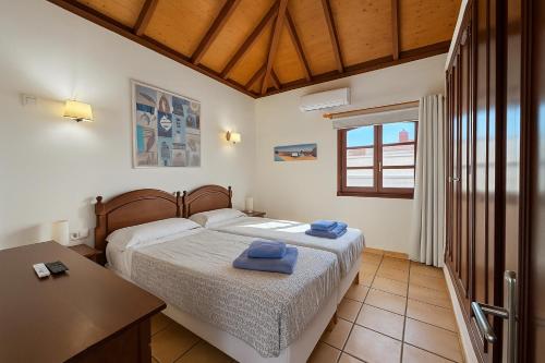 a bedroom with two beds and a table and a window at Villa Corralejo Beach in Corralejo