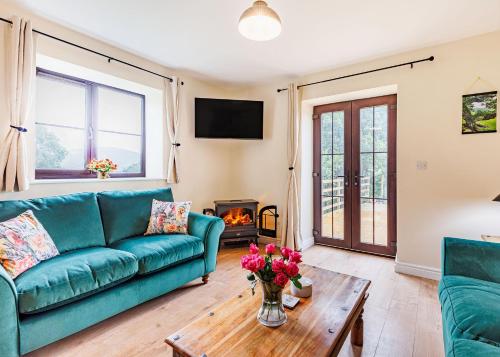 a living room with a blue couch and a fireplace at Sgubor Fach in Pen-y-bont-fawr