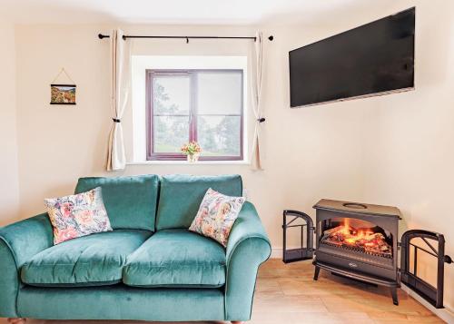 a living room with a green couch and a fireplace at Sgubor Fach in Pen-y-bont-fawr