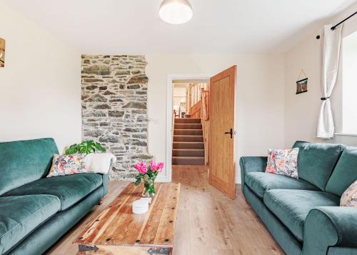 a living room with two green couches and a table at Sgubor Fach in Pen-y-bont-fawr