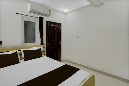 a bedroom with a bed and a window and a door at Hotel O De' BVL Grand in Hyderabad