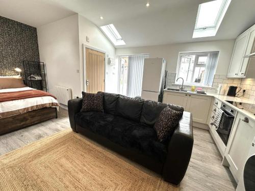 - un salon avec un canapé noir et un lit dans l'établissement Brain Properties Limited - Garden flat with Parking near QA Hospital, à Portsmouth
