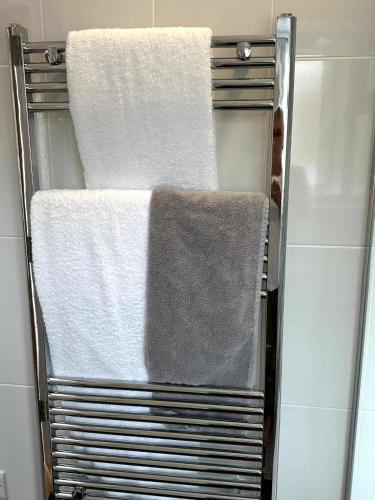 a towel rack with four towels on it in a bathroom at Brain Properties Limited - Garden flat with Parking near QA Hospital in Portsmouth