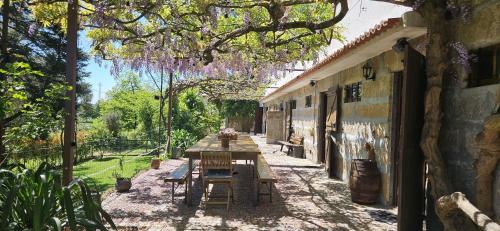 a patio with a table and a tree with purple flowers at Casa da Alvarinha. Privacidade, Conforto, Natureza in Paredes