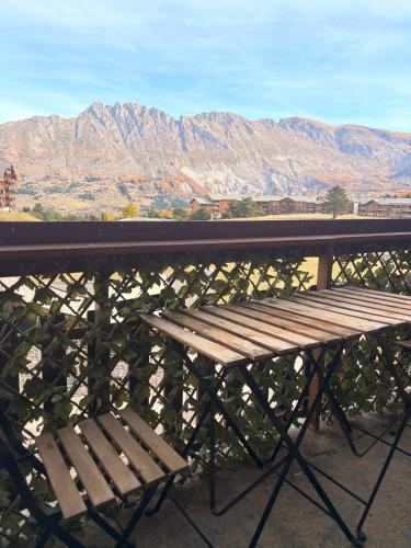 a wooden bench sitting on a balcony with mountains at Studio familial, chaleureux, pied des pistes, 5e étage, côté calme in Superdevoluy