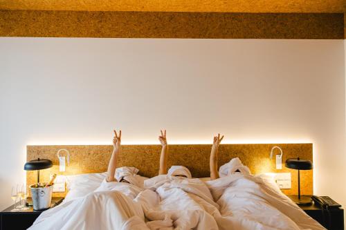 three people laying in bed with their arms in the air at Canadiano Urban Nature Hotel in Ponta Delgada
