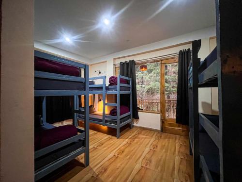 a room with several bunk beds and a window at Yellow Stone Cottage and Cafe in Jibhi