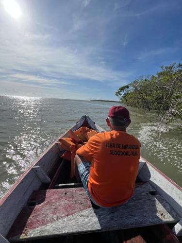 a man sitting in a boat on the water at Pousada Rosa de Saron - Algodoal in Algodoal