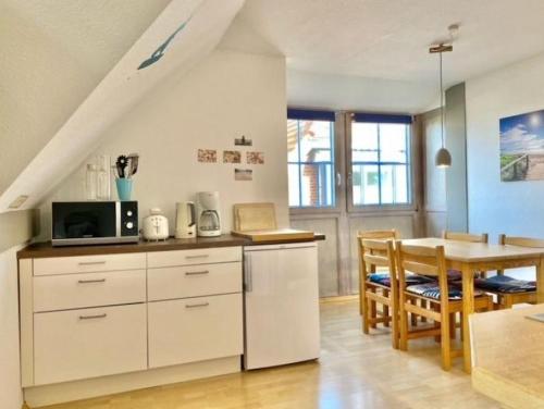 - une cuisine et une salle à manger avec des placards blancs et une table dans l'établissement Kajüte 4, à Lemkenhafen auf Fehmarn