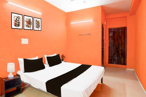 a bedroom with a bed with an orange wall at HOTEL O PRAGYA 6 in Raipur