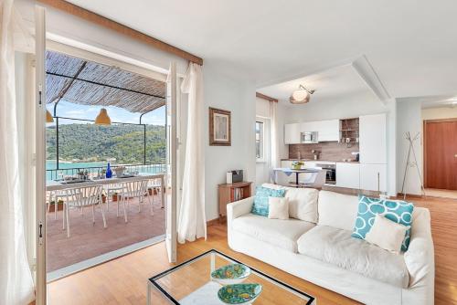 a living room with a white couch and a kitchen at Porto sea view-Terrace & AC in Portovenere