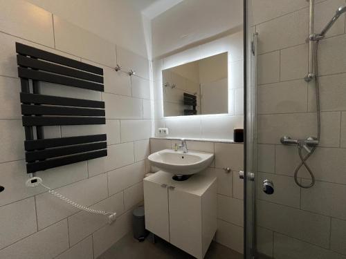 une salle de bain blanche avec un lavabo et un miroir dans l'établissement L36EG links, à Lemkenhafen auf Fehmarn