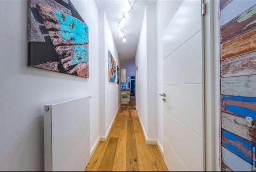a hallway with white walls and wooden floors and paintings at Surf and Chill in Orth