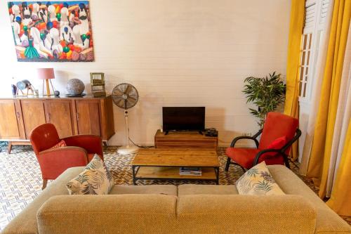 a living room with a couch and red chairs at La Maison Jaune - Swimming pool & beach access 50 m away in Saint-Pierre